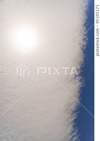 Fluffy clouds in the blue sky, they are arranged in a flat strip. The sun shines through them. Fluffy clouds in the blue sky, they are arranged in a flat strip. The sun shines through them. 95105171