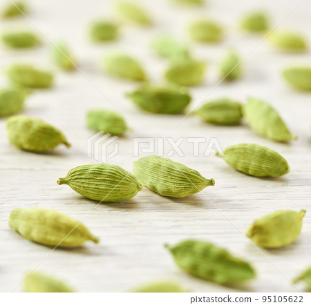 close up cardamom pods on a white wooden table, selective focus. close up cardamom pods on a white wooden table, selective focus. 95105622