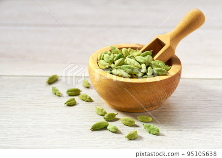 Cardamom pods on a white wooden kitchen table, selective focus. 95105638