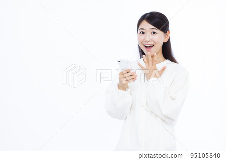 A woman in her thirties who is surprised with a smile holding a smartphone A woman in her thirties who is surprised with a smile holding a smartphone 95105840