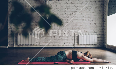 Young woman in trendy sportswear is practicing yoga during individual practice in modern wellness center. She is doing sequence of popular asanas. Personal yoga training concept. 95106149