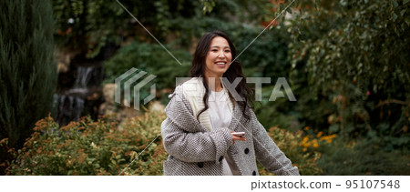 Portrait of pretty asian kazakh brunette woman with charming smile walking along outdoors Portrait of pretty asian kazakh brunette woman with charming smile walking along outdoors 95107548