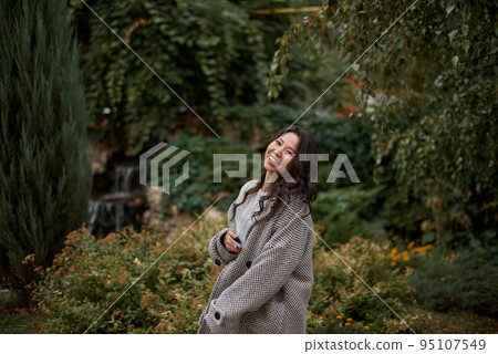 Portrait of pretty asian kazakh brunette woman with charming smile walking along outdoors Portrait of pretty asian kazakh brunette woman with charming smile walking along outdoors 95107549