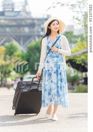 A young woman pulling a suitcase and sightseeing in Nagoya 95107882