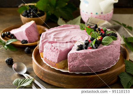 Cake with Black Currant Cream Souffle and Biscuit on a table in a rustic style. 95110153