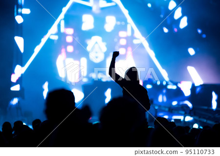 Crowd of people with arms outstretched partying at an EDM concert 95110733