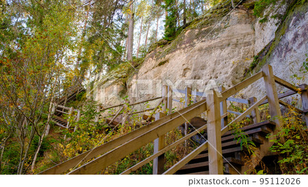 The large sandstone cliffs of Sietiniezis on the banks of the Gauja River in Latvia. tourist nature trail for hiking with wooden stairs. Gauja National Park in the vicinity of Valmiera, Autumn, The large sandstone cliffs of Sietiniezis on the banks of the Gauja River in Latvia. tourist nature trail for hiking with wooden stairs. Gauja National Park in the vicinity of Valmiera, Autumn, 95112026