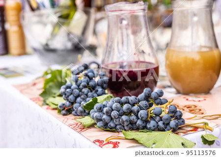 Fresh red grapes with jars of red wine and a traditional young wine burciak - burcak Fresh red grapes with jars of red wine and a traditional young wine burciak - burcak 95113576