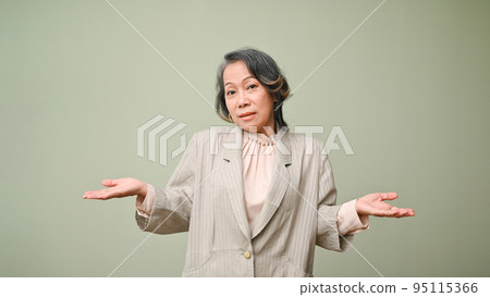 Uncertain and confused 60s aged asian woman shrugging her shoulders, isolated background. no idea 95115366