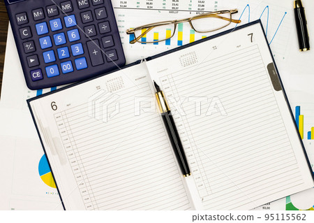 Top view office table desk. Financial report. Flat lay. Workspace with Business office supplies, numbers and empty sheet of diary, diagrams, pen, glasses, calculator. Copy space for text. Top view 95115562