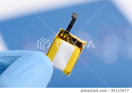 Scientist hold in fingers and show very small rechargeable lithium Li-ion battery with connector Scientist hold in fingers and show very small rechargeable lithium Li-ion battery with connector 95115677