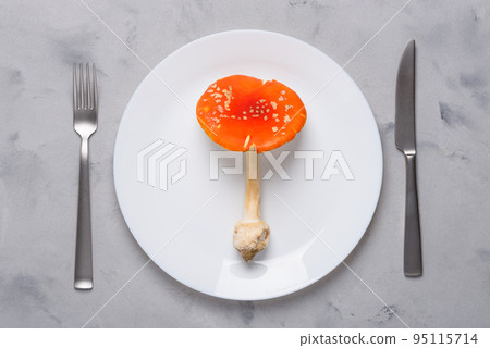 Amanita muscaria fly agaric poisonous mushroom on plate with fork and knife top view. Amanita muscaria fly agaric poisonous mushroom on plate with fork and knife top view. 95115714