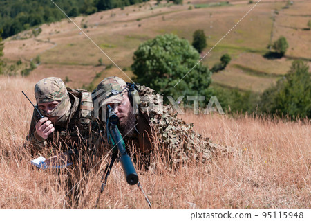 Sniper soldier assisted by an assistant to observe the area to be targeted with modern warfare tactical virtual reality goggles aerial drone military technology. 95115948