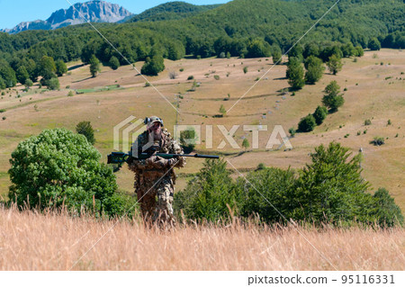 army soldier holding a sniper rifle with scope and walking in the forest. war, army, technology and people concept. army soldier holding a sniper rifle with scope and walking in the forest. war, army, technology and people concept. 95116331