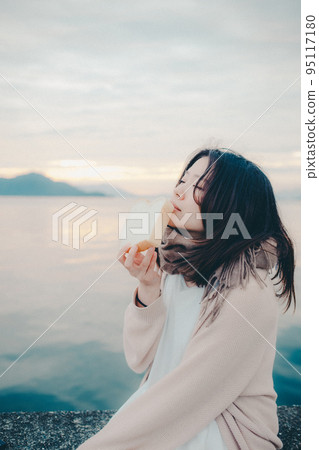 Photo of a woman eating bread with a beautiful sunrise Photo of a woman eating bread with a beautiful sunrise 95117180