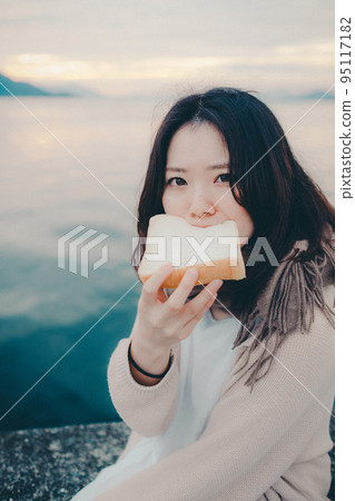 一個女人在美麗的日出中吃麵包的照片 一個女人在美麗的日出中吃麵包的照片 95117182