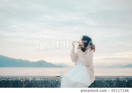一個女人在美麗的日出中吃麵包的照片 95117186