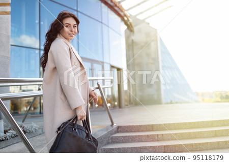 successful business woman enters the business center with a briefcase in her hands, strong and 95118179