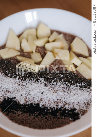 Vegan raw flaxeed porridge with fruits and chia, black sesame and psyllium seeds, coconut flakes. Healthy nutritious and fresh food. Close-up Vegan raw flaxeed porridge with fruits and chia, black sesame and psyllium seeds, coconut flakes. Healthy nutritious and fresh food. Close-up 95118397