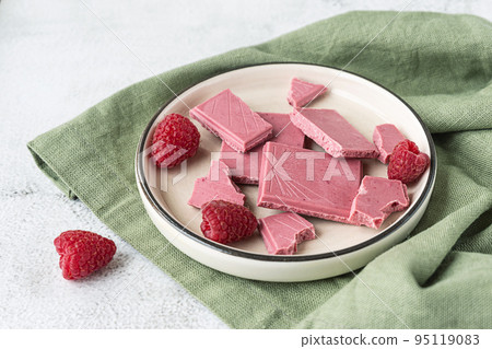 Pink or ruby chocolate, trendy dessert on a white plate with raspberries Pink or ruby chocolate, trendy dessert on a white plate with raspberries 95119083