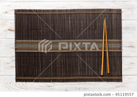 Two chopsticks and bamboo mat on wooden background. Top view, copy space 95119557