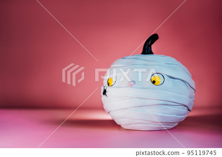Funny and cute pumpkin mummy with spider on the pink background. White Pumpkin with Confused and worried look. Halloween decor and background with copy space. Selective focus. 95119745