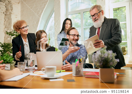 Group of mixed ages people talking, working with colleagues, co-workers at loft style office. Business, urban lifestyle, work, finance, tech concept. 95119814