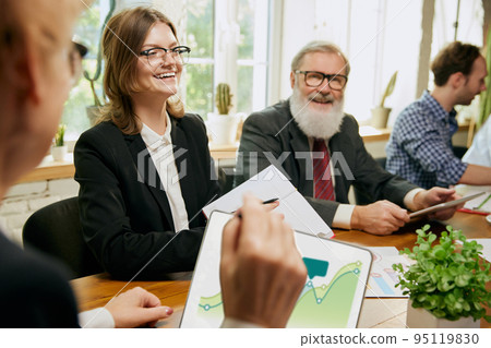 Group of mixed ages people talking, working with colleagues, co-workers at loft style office. Business, urban lifestyle, work, finance, tech concept. 95119830