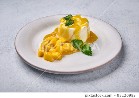Panna cotta with natural vanilla pod, mango syrup and mint, high key Panna cotta with natural vanilla pod, mango syrup and mint, high key 95120982