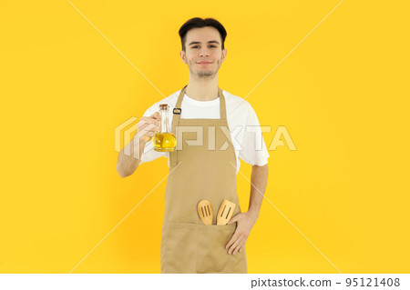 Concept of cooking, young man chef on yellow background 95121408