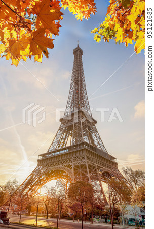 Eiffel Tower with autumn leaves against colorful sunset in Paris, France 95121685