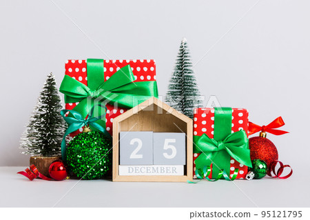 25 december. Christmas composition on colored background with a wooden calendar, with a gift box, toys, bauble copy space 95121795