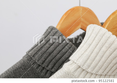 Sweaters hang on hangers on light background, close up 95122581