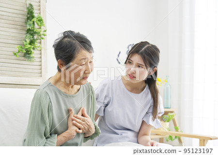 Elderly woman feeling palpitations in the living room Elderly woman feeling palpitations in the living room 95123197