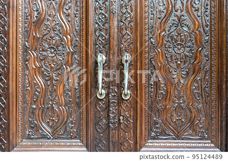 Engraved wooden doors of an old classic cabinet. Antique wooden textures concept. 95124489