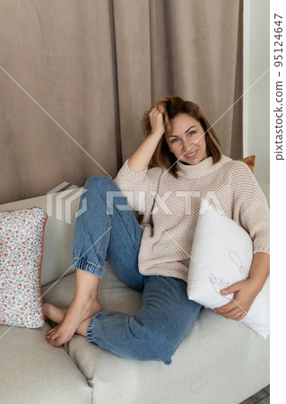 charismatic girl sits on the couch in a comfortable position bend her legs under her charismatic girl sits on the couch in a comfortable position bend her legs under her 95124647