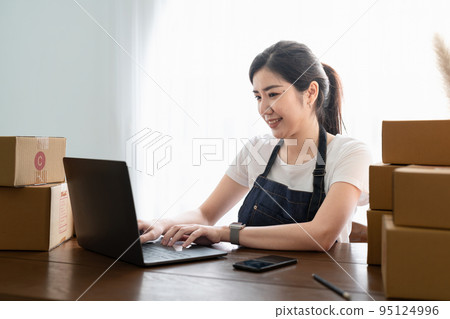Small Business Startup, SME Owner, Female Entrepreneur work on parcel boxes Receipts and check orders online to prepare boxes. Selling to customers. Online SME business idea. 95124996