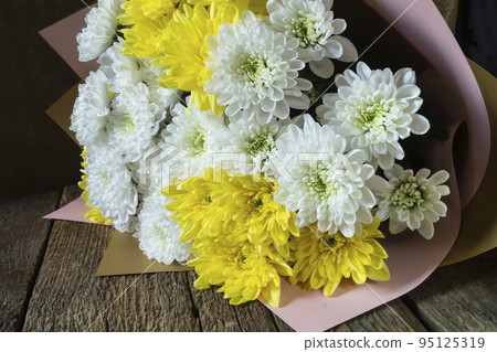 White and yellow chrysanthemums on a wooden table 95125319