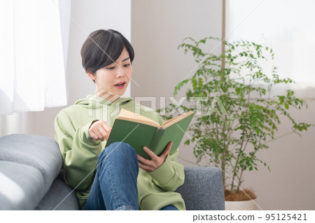 Young woman reading a book in the living room Young woman reading a book in the living room 95125421