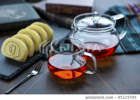 Tea in a glass cup and roll cake on a slate plate Tea in a glass cup and roll cake on a slate plate 95125595