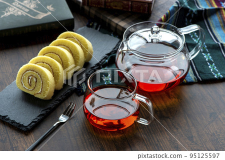 Tea in a glass cup and roll cake on a slate plate Tea in a glass cup and roll cake on a slate plate 95125597