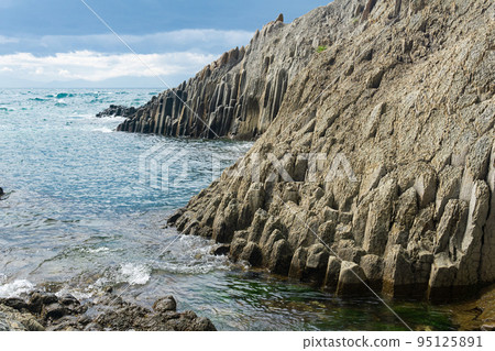 natural landscape with a sheer cliff folded columnar basalt on the seashore 95125891