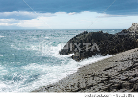 rocky seashore formed by columnar basalt against the surf, coastal landscape of the Kuril Islands rocky seashore formed by columnar basalt against the surf, coastal landscape of the Kuril Islands 95125892