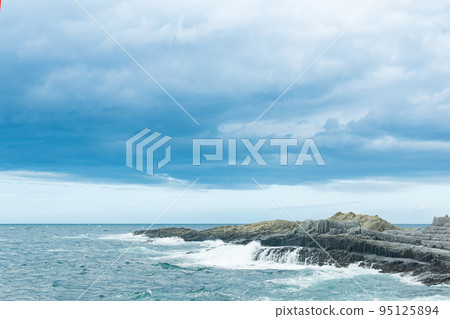 rocky seashore formed by columnar basalt against the backdrop of a stormy sea, coastal landscape of the Kuril Islands rocky seashore formed by columnar basalt against the backdrop of a stormy sea, coastal landscape of the Kuril Islands 95125894