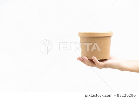 Hand of business woman hold blank brown paper packaging on white concrete background Hand of business woman hold blank brown paper packaging on white concrete background 95126290