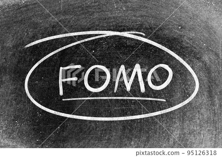 White chalk hand writing in word FOMO (abbreviation of fear of missing out) and circle shape on blackboard background 95126318