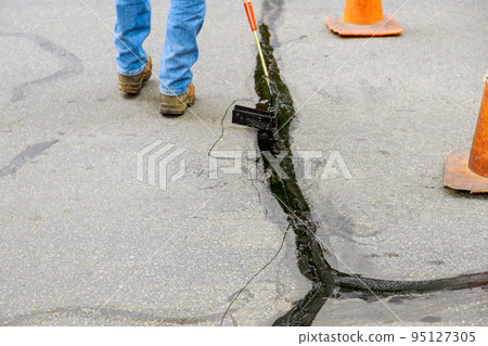 An asphaltic joint crack needs to be sealed in restoration work asphalt road surface 95127305