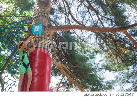adventure climbing high wire park - people on course in mountain helmet and safety equipment. High quality photo 95127547