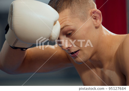 Young athlete, male boxer on break from exercise and training on the floor of sports gym. Young athlete, male boxer on break from exercise and training on the floor of sports gym. 95127684
