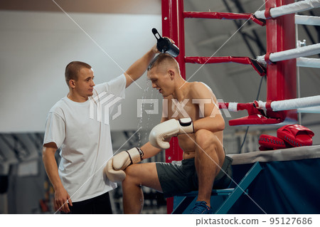 Professional boxer training with personal coach, trainer at boxing ring at sports gym. Sport, strategy, studying, skills and achievements 95127686